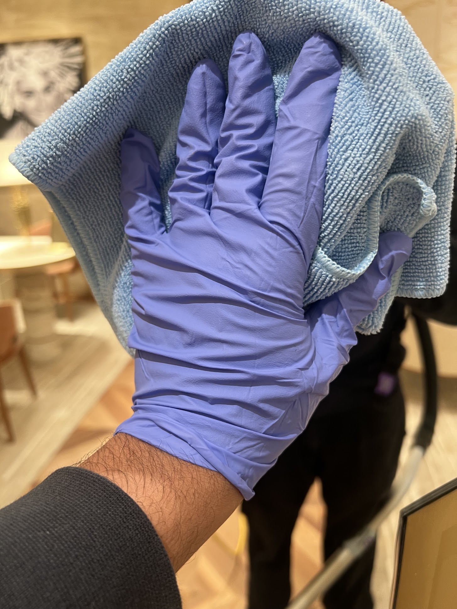 Gloved cleaner detailing a surface with a microfibre cloth in a luxury space
